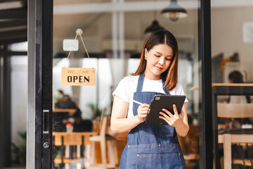 Happy excited attractive young Asian woman in denim apron, received online order in coffee shop...