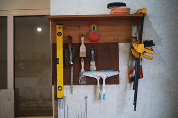 An organized tool rack holds essential woodworking tools, a level, saws, and clamps, reflecting a well-maintained and efficient workspace.