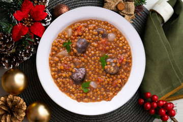 Lentils with chorizo ​​and black blood sausage. Christmas food served on a table decorated with Christmas motifs.