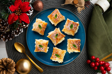 Miguelitos de la Rueda. Traditional Spanish dessert made with puff pastry and cream filling. Christmas food served on a table decorated with Christmas motifs.