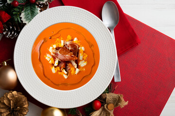 Traditional spanish salmorejo. Cold tomato soup served with egg and iberico jam. Christmas food served on a table decorated with Christmas motifs.