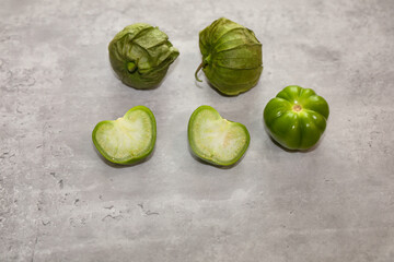 Mexican husk tomatoes also known as green tomatillos with the husk, whole without husk and cut in half.