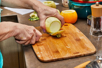 Chef cuts round zucchini on wooden board in the home kitchen