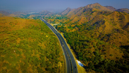 Aerial of a highway or expressway through low rise mountains