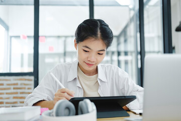 Young collage student using computer and mobile device studying online...