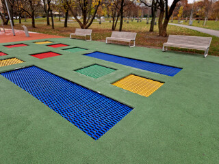 courtyard of school playground, three trampoline jumping mats are sunk below level of a special...