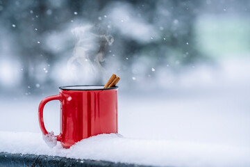 Mulled wine cup in winter forest. Winter hot drinks with aromatic spices of cinnamon, cardamom and orange. Warmth, comfort and atmosphere of December nature and Christmas