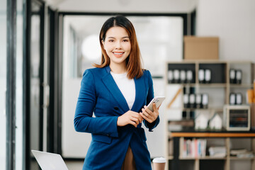 Young attractive Asian female office worker business suits smiling at camera in office .