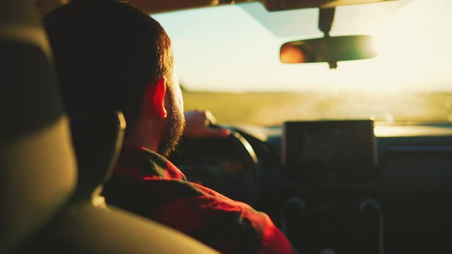 Rear view in saloon auto on male who driving on rural road. Blurred view from front window car and rear view inside mirror. Summer travel by transport outside city on uneven sections bumps and pits.