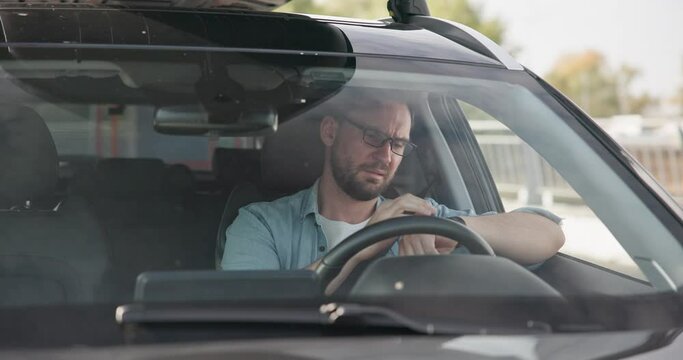 Sad angry man sitting in a car in a traffic jam and gesticulating angrily in impatience and irritation