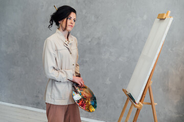 A woman artist at an easel in an art studio paints a picture