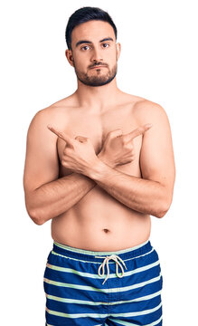 Young handsome man wearing swimwear pointing to both sides with fingers, different direction disagree
