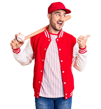 Young handsome man holding baseball bat and ball pointing thumb up to the side smiling happy with open mouth