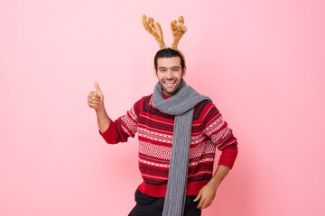 Christmas studio shot portrait of smiling Caucasian man wearing sweater and fancy reindeer headband...