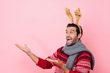 Christmas studio shot portrait of smiling Caucasian man wearing sweater and fancy reindeer headband...
