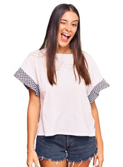 Young hispanic woman wearing casual clothes winking looking at the camera with sexy expression, cheerful and happy face.