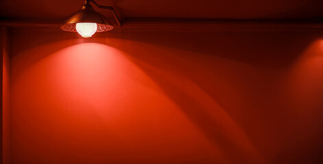 Illuminated Light Hanging Against red Wall. hanged ceiling lamp warm tone light color bulb light with dark red tone concrete background wall