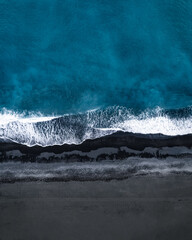 aeriel view of ocean waves on black sand beach