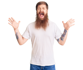 Handsome young red head man with long beard wearing casual white tshirt celebrating mad and crazy for success with arms raised and closed eyes screaming excited. winner concept