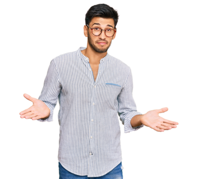 Young handsome man wearing casual clothes and glasses clueless and confused expression with arms and hands raised. doubt concept.