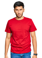 Young handsome man wearing casual red tshirt skeptic and nervous, frowning upset because of problem. negative person.