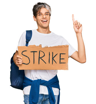 Young hispanic man holding strike banner cardboard surprised with an idea or question pointing finger with happy face, number one