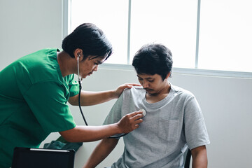 Asian male doctor using a stethoscope listen to the heartbeat of the patient sitting in clinic