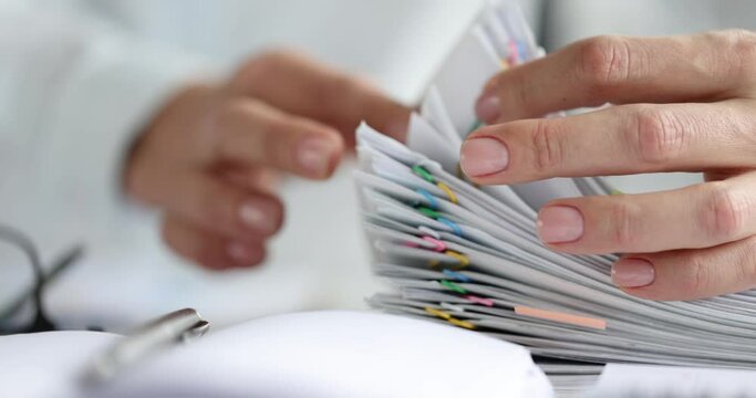 Woman sorting paper documents with colorful paper clips closeup 4k movie slow motion. Paper work concept