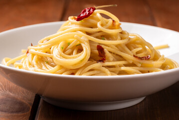 Piatto di tipici spaghetti conditi con aglio, olio e peperoncino, cibo italiano 