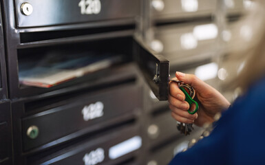 Woman checking mailbox in apartment building.