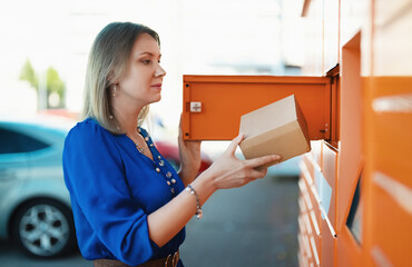 Woman sending or receiving mail via automated self-service pos terminal machine.