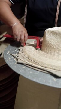 Cutting the brim of a traditional natural fiber hat. Concept of handmade traditional clothing