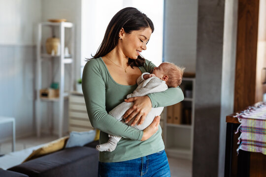 Pretty woman holding a newborn baby in her arms. Single mother parent concept.