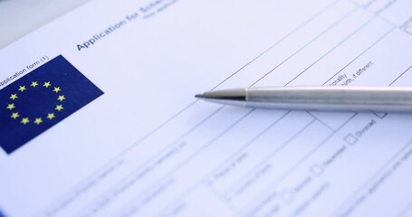 Ballpoint pen lying on table with schengen visa application 4k movie slow motion. European Union travel permit concept - Powered by Adobe