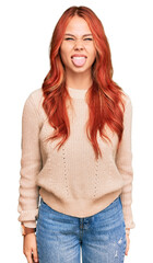 Fototapeta premium Young redhead woman wearing casual winter sweater sticking tongue out happy with funny expression. emotion concept.