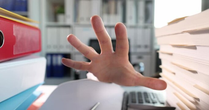 Man hand reaches along documents and folders on desktop. 