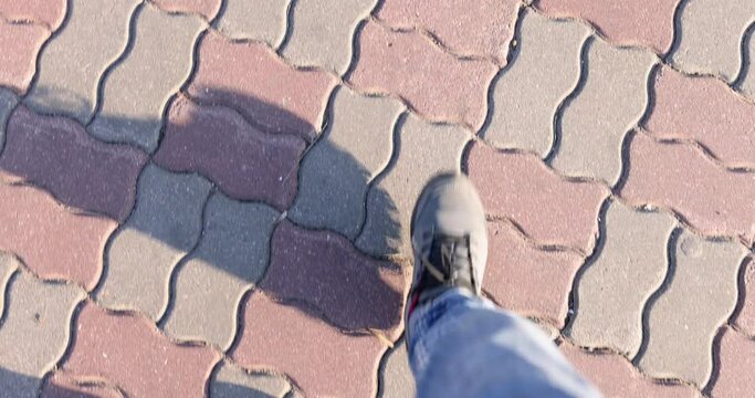 Male feet in jeans and warm shoes walk along paving slabs. Hiking health concept