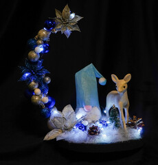 Christmas wreath in the form of a star Blue lights. Symbolic Christmas balls and ornaments. Green, white. On a black background