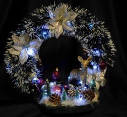 Christmas wreath in the form of a star Blue lights. Symbolic Christmas balls and ornaments. Green, white. On a black background