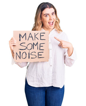Young caucasian woman holding make some noise banner smiling happy pointing with hand and finger