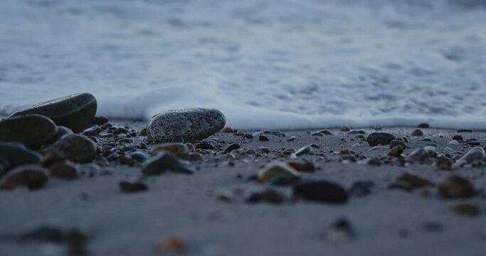 Close up of waves rushing over rocks on a beach.