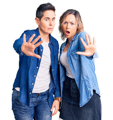 Couple of women wearing casual clothes doing stop gesture with hands palms, angry and frustration expression
