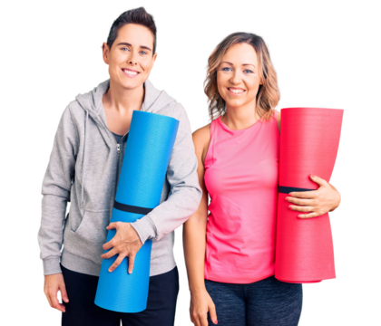 Couple of women holding yoga mat looking positive and happy standing and smiling with a confident smile showing teeth