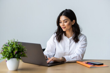 Concentrated young beautiful businesswoman working on laptop in modern office