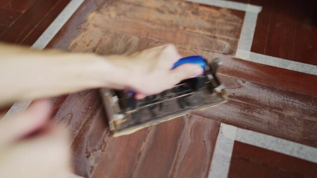 Sanding wooden floor with sandpaper holder