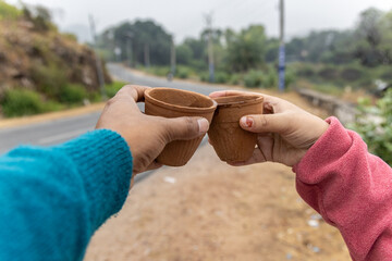 couple enjoying hot tea served in traditional pottery clay cup with blurred highway landscape