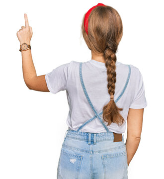 Young caucasian girl wearing casual clothes posing backwards pointing ahead with finger hand