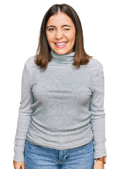 Young beautiful woman wearing casual turtleneck sweater winking looking at the camera with sexy...
