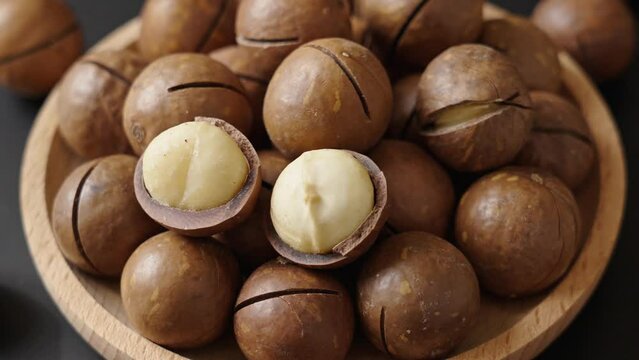 Close up macadamia nuts in plate on black background