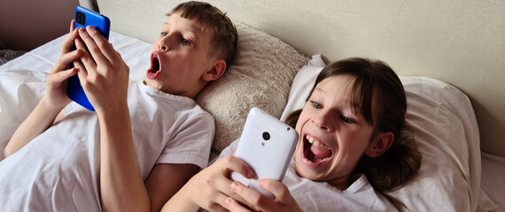 Surprised shocked kids with mobile phone play online games - obrazy, fototapety, plakaty